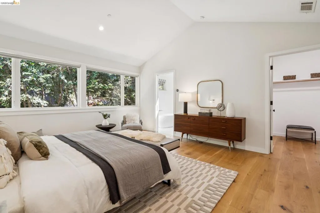 Vaulted white ceilings, wood-finish flooring, recessed lighting, and a wide window wall Vaulted white ceilings, wood-finish flooring, recessed lighting, and a wide window wall