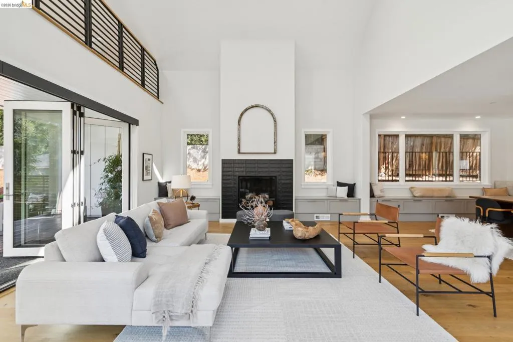Vaulted ceiling living area featuring a dark tile fireplace, wood-finish flooring, and expansive glass sliding doors Vaulted ceiling living area featuring a dark tile fireplace, wood-finish flooring, and expansive glass sliding doors