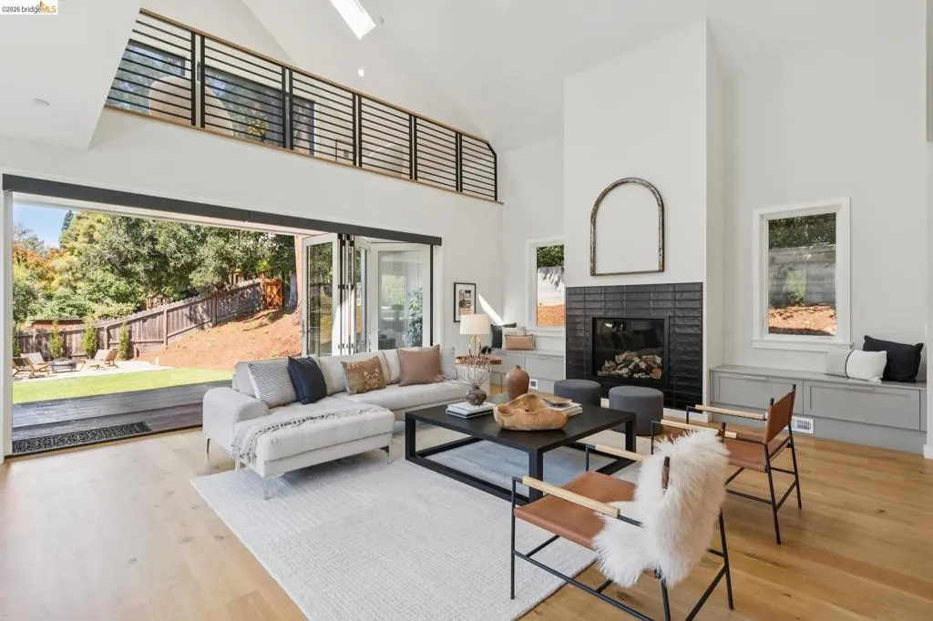 Vaulted ceiling featuring a skylight, wood-finish flooring, and a fireplace with a black tile surround Vaulted ceiling featuring a skylight, wood-finish flooring, and a fireplace with a black tile surround