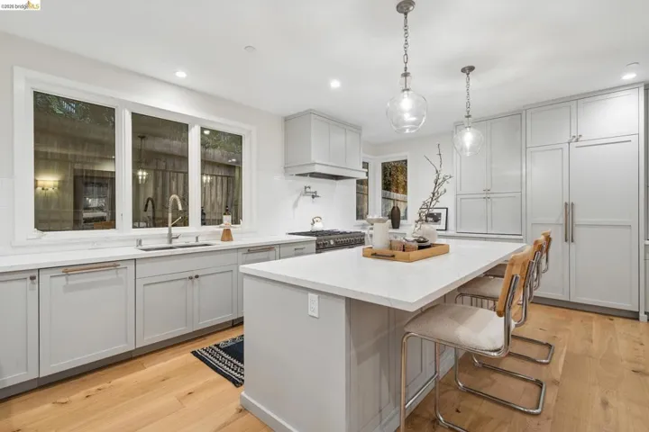 Light-toned wood-finish flooring, white countertops, gray cabinetry, recessed lighting, and a kitchen island with pendant lighting