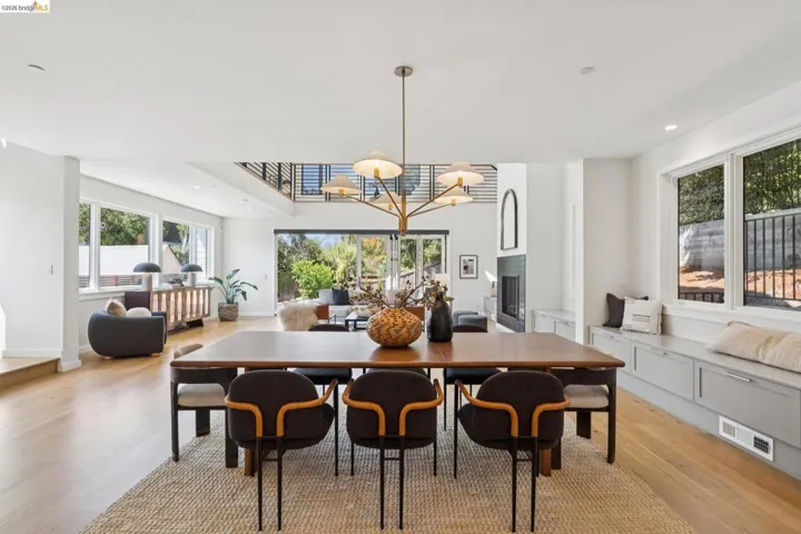 Expansive open-concept living area featuring wood-finish flooring, a contemporary chandelier, and a built-in window bench with storage