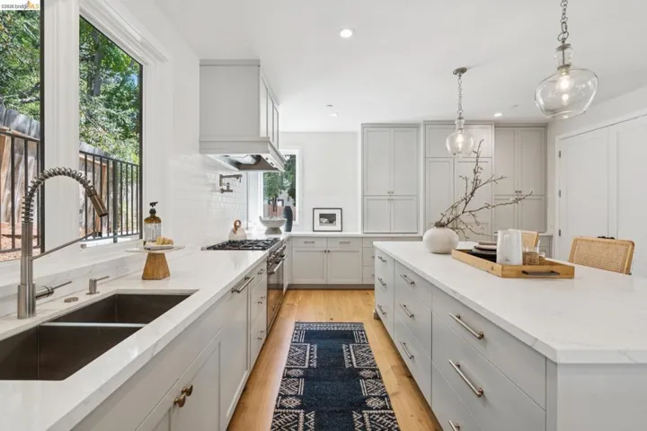 Gourmet kitchen featuring a large island with seating, pendant lighting, stainless steel appliances, and light wood-finish flooring