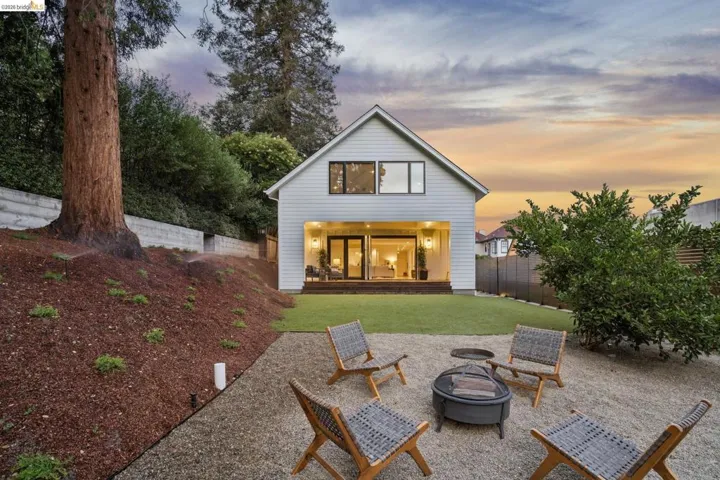 Backyard featuring a green lawn, gravel patio, and sloped landscaping