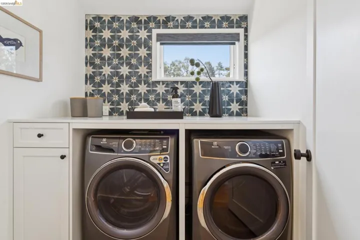 Built-in cabinetry, integrated appliances, and patterned tile backsplash with a window