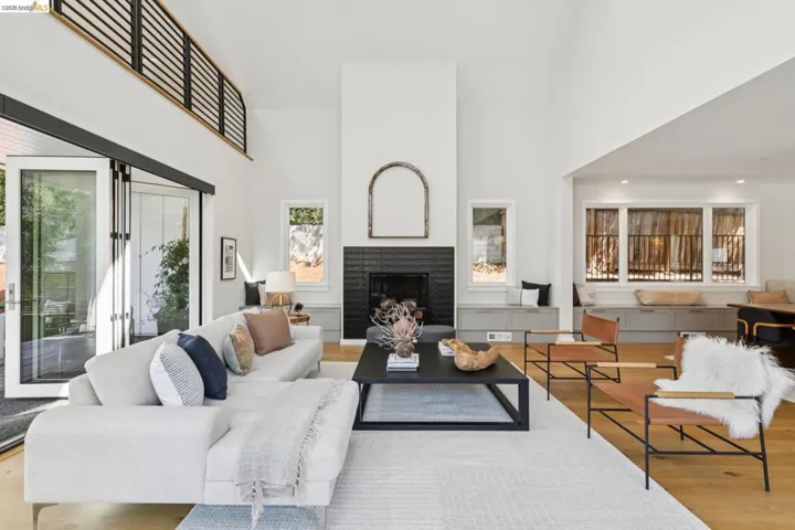 Vaulted ceiling living area featuring a dark tile fireplace, wood-finish flooring, and expansive glass sliding doors