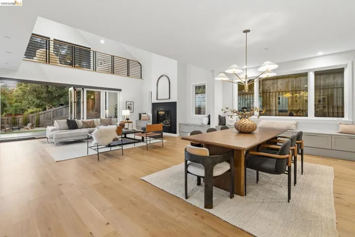 Spacious open-concept living area featuring light wood-finish flooring, a fireplace with a dark surround, and a two-story vaulted ceiling