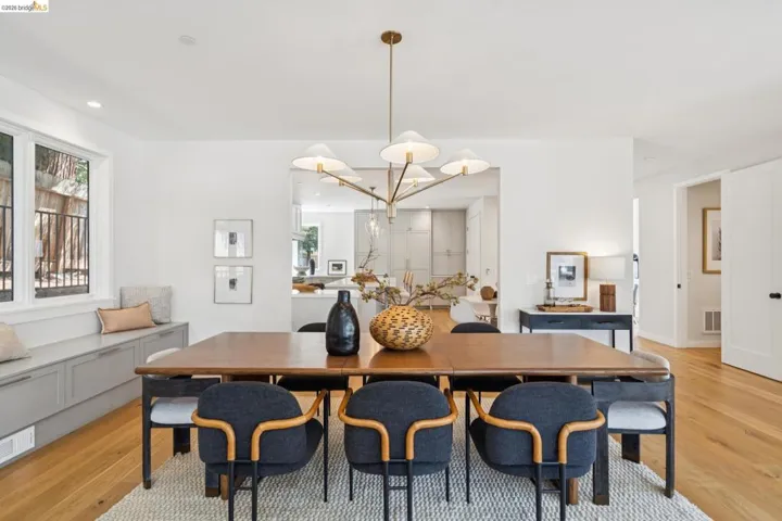 Open-concept dining area featuring wood-finish flooring, a contemporary chandelier, and a built-in window bench with integrated storage