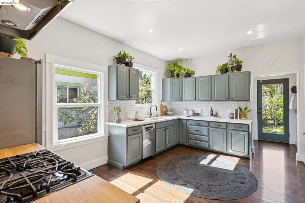 Kitchen featuring L-shaped cabinetry with shaker-style doors, white countertops, hexagon tile backsplash, and dark wood-finish flooring