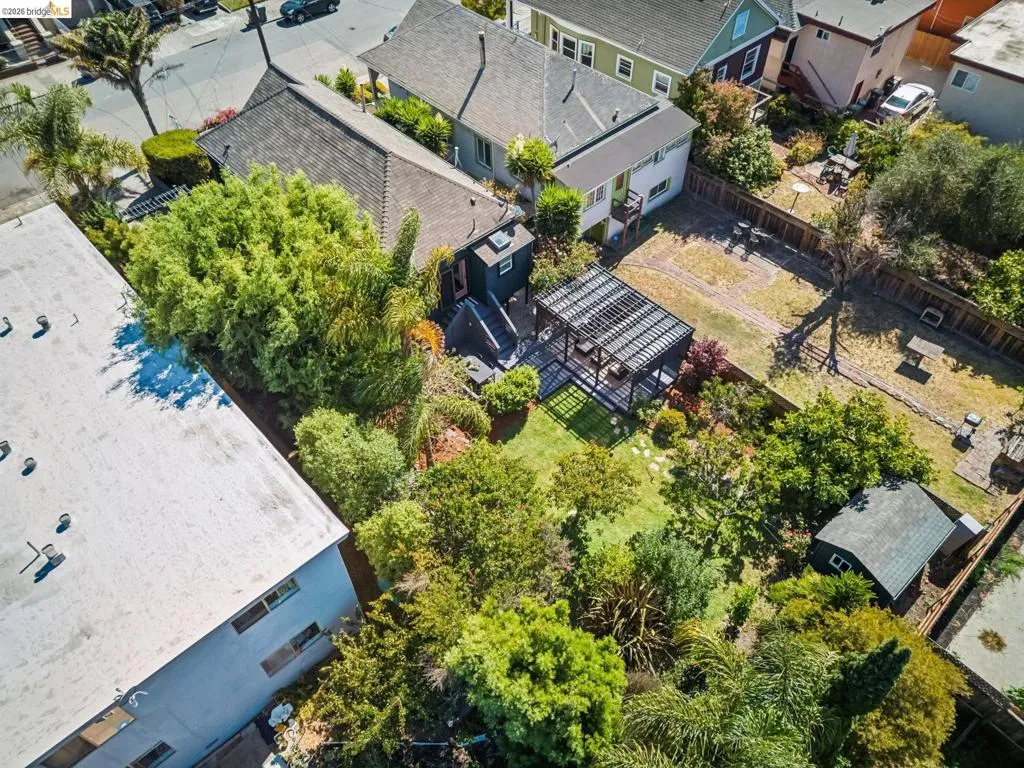 Landscaped backyard with a dark-stained pergola, lush greenery, and a detached shed