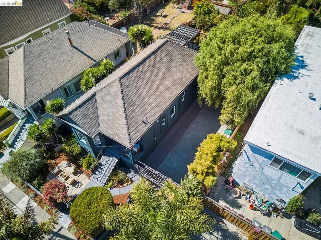Gable roofline, mature trees, pergola, paved driveway, and established landscaping