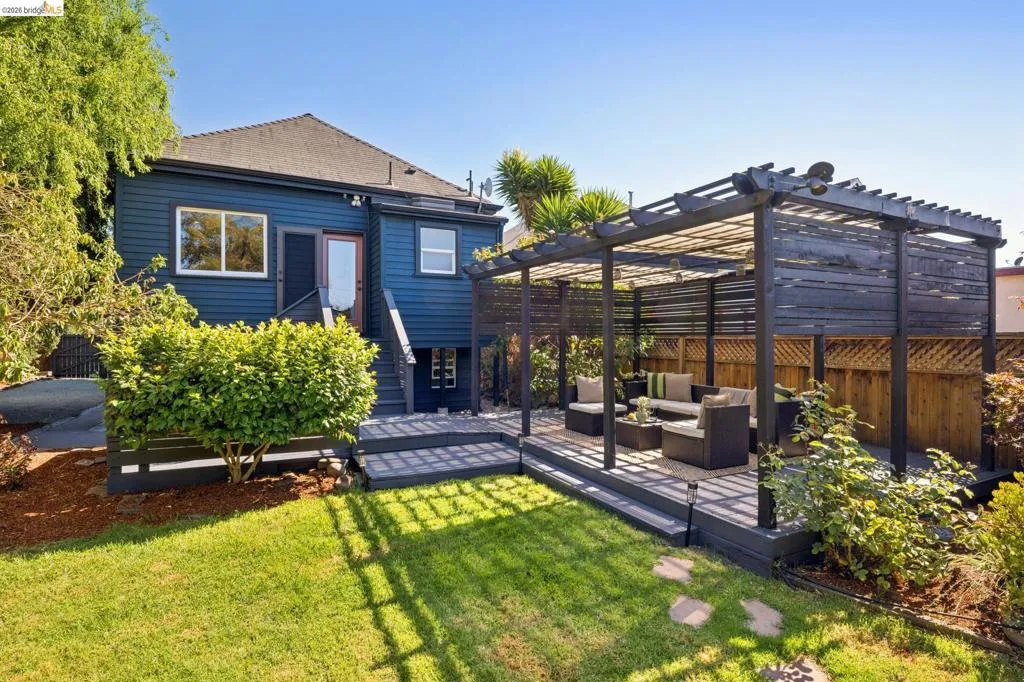 Expansive backyard featuring a pergola-covered patio, wooden privacy fencing, a manicured lawn, and mature landscaping