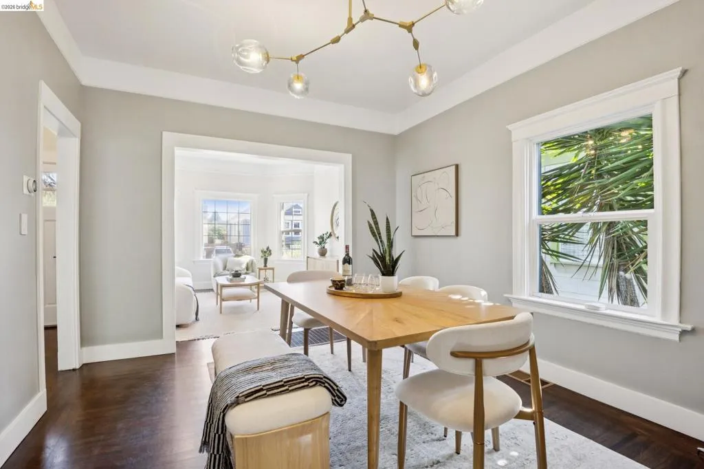Dining area featuring dark wood-finish flooring, a contemporary chandelier, and bright window