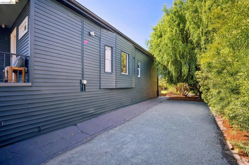 Exterior featuring dark-toned horizontal siding, multiple windows, and a gravel pathway