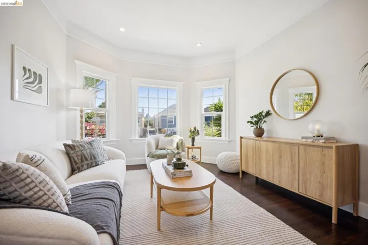 Dark wood-finish flooring, light tone area rug, recessed lighting, crown molding, and bay windows
