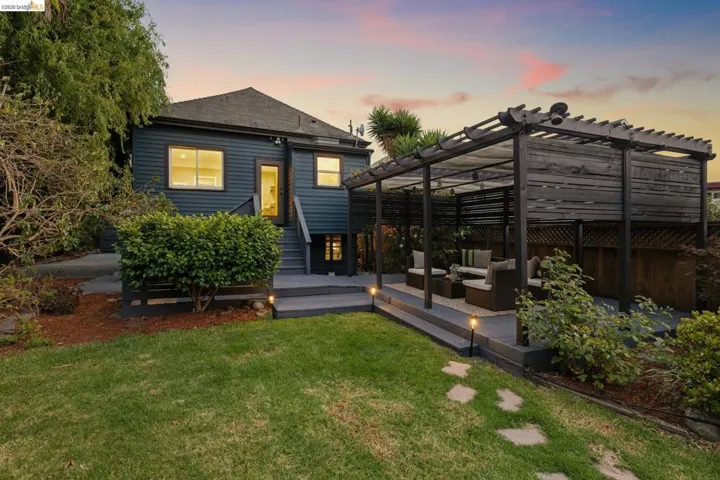 Expansive backyard featuring a manicured lawn, a multi-tiered deck, and a spacious pergola with slatted wood accents