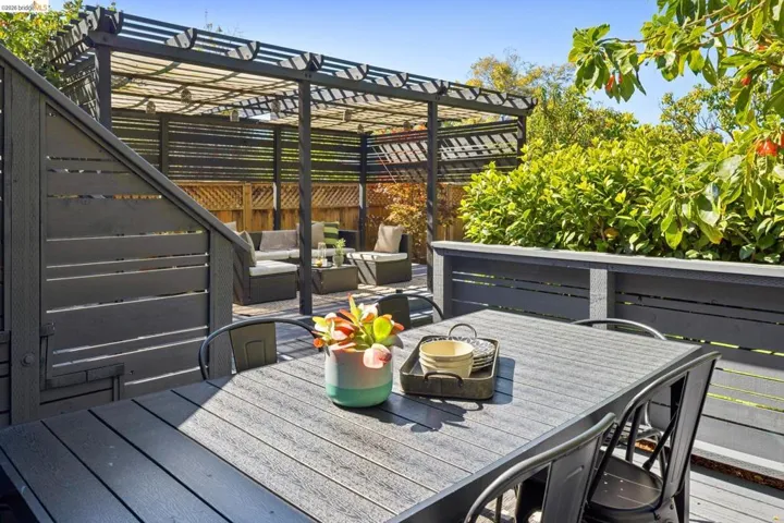 Multi-level outdoor deck featuring a slatted pergola, privacy fencing, and mature landscaping