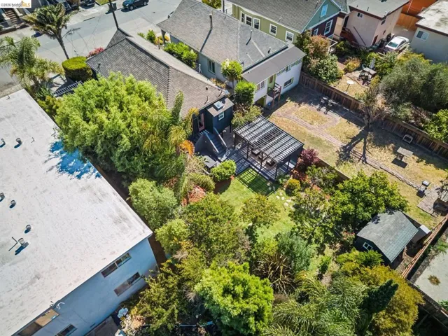 Landscaped backyard with a dark-stained pergola, lush greenery, and a detached shed