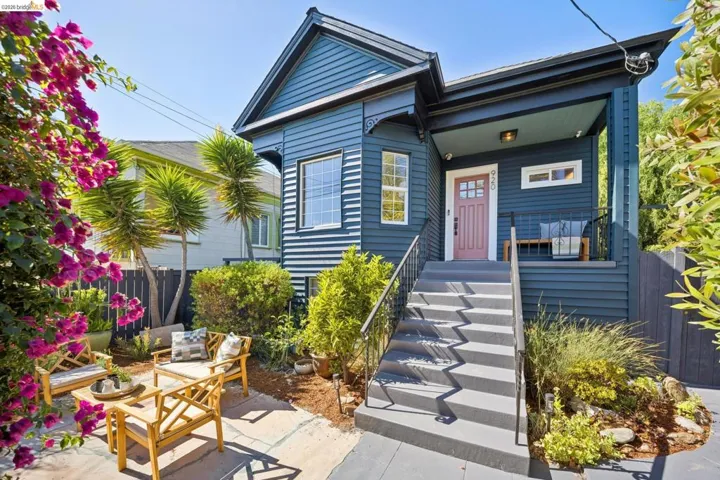 Charming blue cottage featuring a modern gabled roof, covered front entry with concrete steps, and a manicured front courtyard