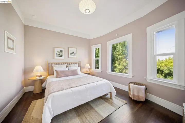 Rich wood-finish flooring, white window trim, and white crown molding complement the light wall color