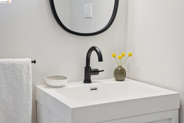 White vanity with integrated sink, matte black faucet, and a circular mirror