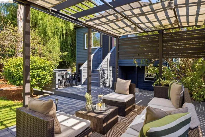 Expansive outdoor deck with a pergola, slatted privacy fence, and adjacent lawn area