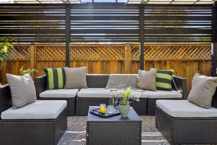 Private outdoor patio featuring a slatted privacy screen, wood fencing, and a patterned area rug