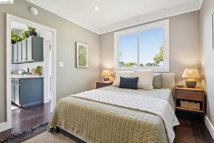 Hardwood-finish flooring, white window trim, grey wall paint, and white crown molding