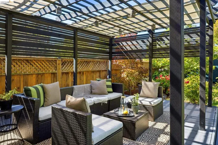 Outdoor living space with a slatted pergola, composite decking, privacy screens, and a wood lattice fence