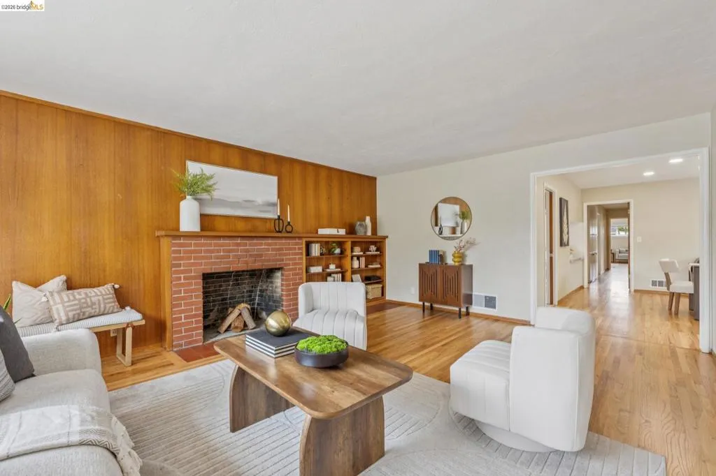 Wood-paneled accent wall, brick fireplace, built-in shelving, and wood-finish flooring