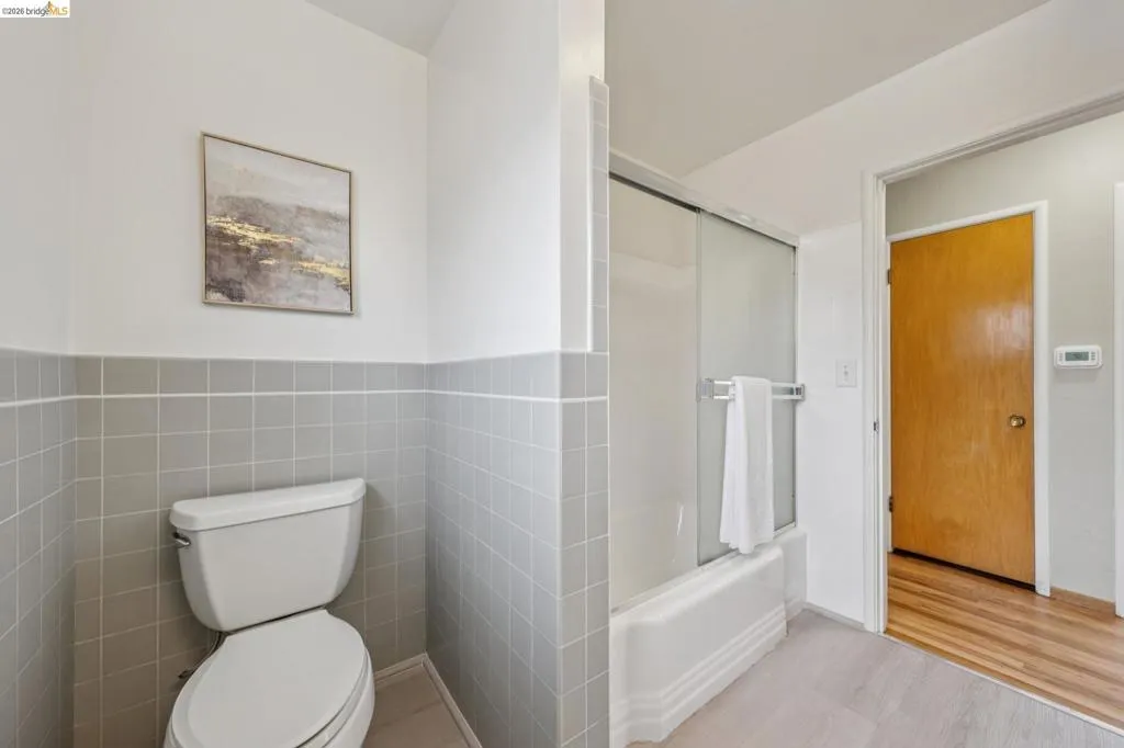 Bathroom with gray tile wainscoting and a white toilet