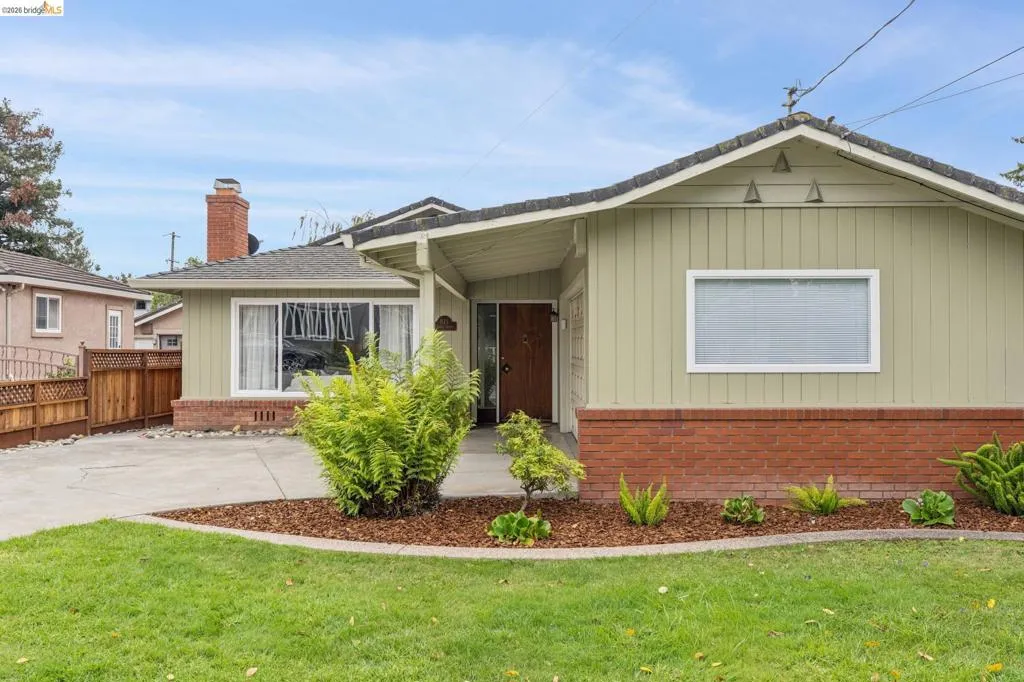 Front elevation with light green vertical siding and brick detailing