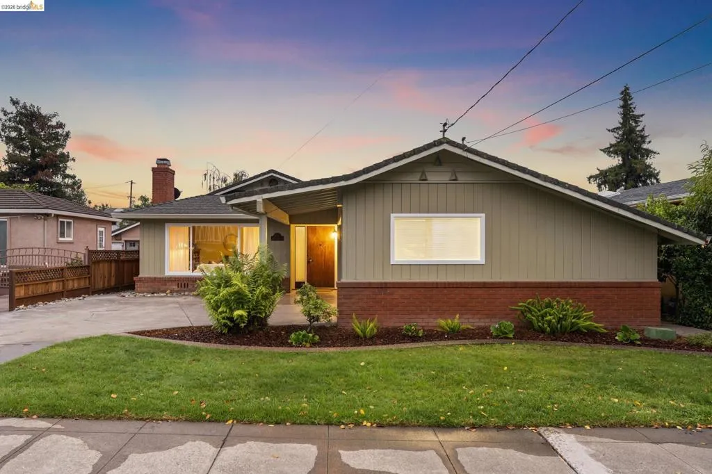 Well-maintained front lawn, mature landscaping, brick foundation, wood siding, and an attached driveway
