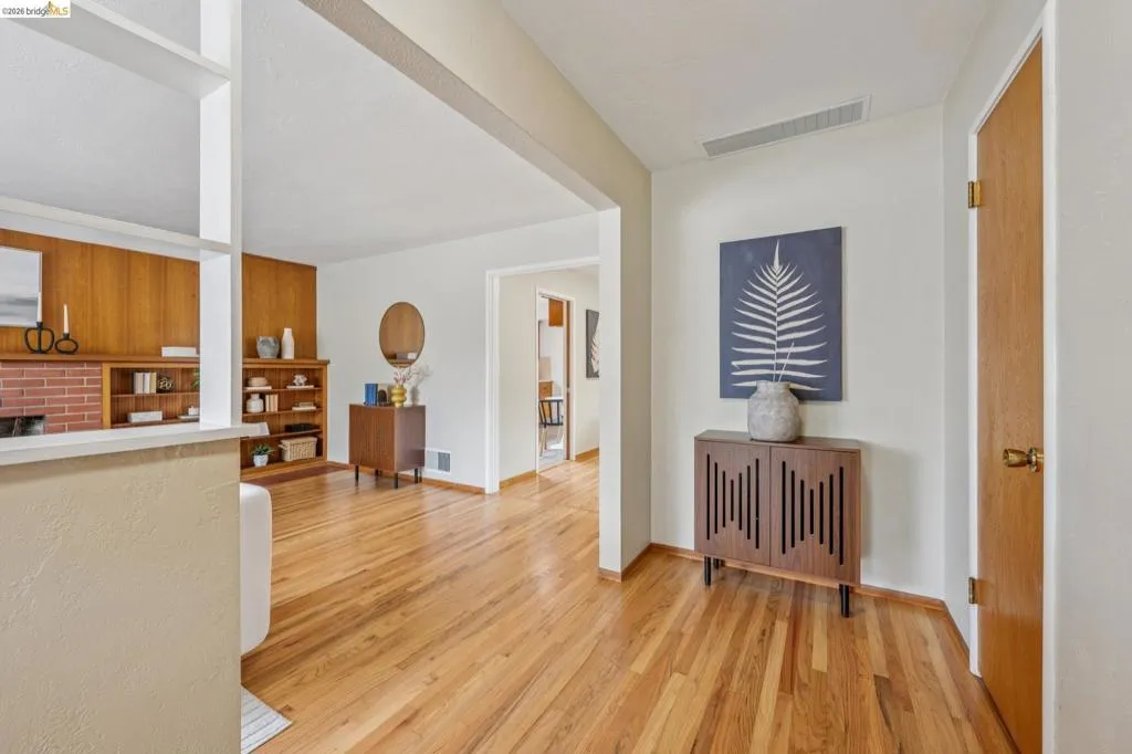 Hardwood flooring, cased openings, built-in shelving, brick fireplace surround, and wood paneling