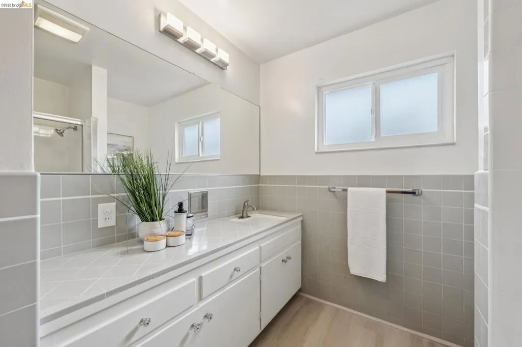 Expansive vanity with integrated sink, white cabinetry, and full-width mirror