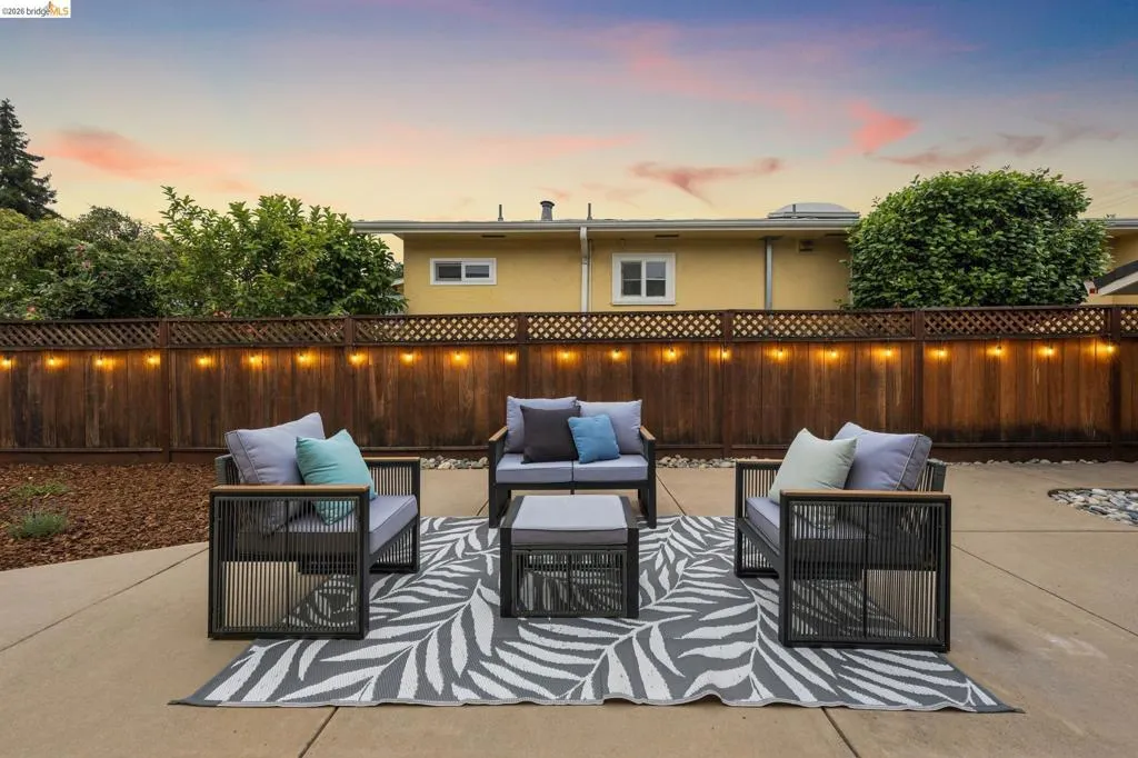 Hardscaping patio surface with a wood-panel fence and lattice top, illuminated by string lighting