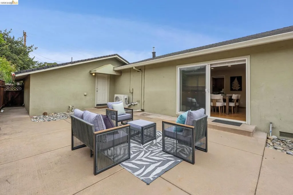 Expansive concrete patio with stucco exterior, sliding glass door, and tiled roof