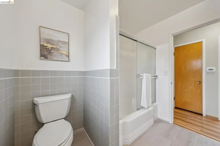 Bathroom with gray tile wainscoting and a white toilet