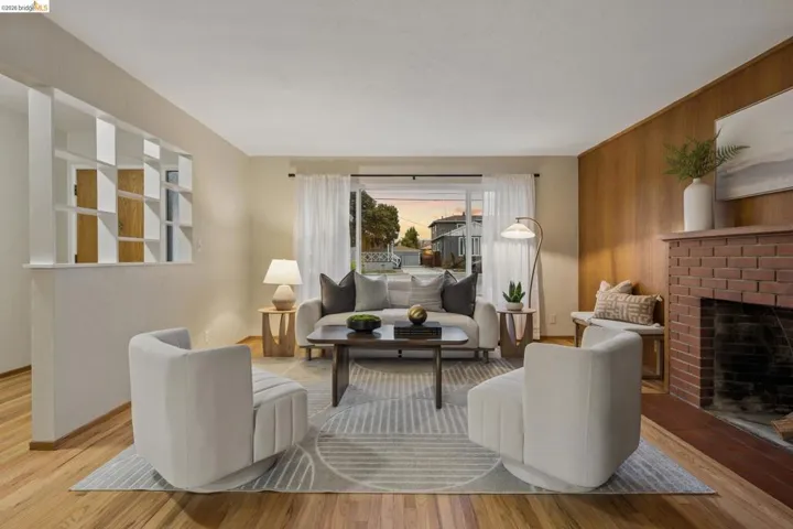 Hardwood flooring throughout, a red brick fireplace with a wood-paneled wall, and a decorative room divider