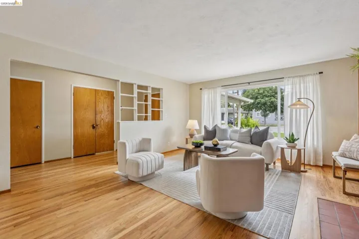 Hardwood flooring, expansive window, built-in shelving, two wood-finish doors, and a fireplace hearth