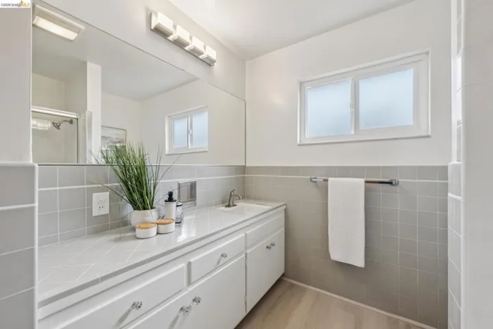 Expansive vanity with integrated sink, white cabinetry, and full-width mirror