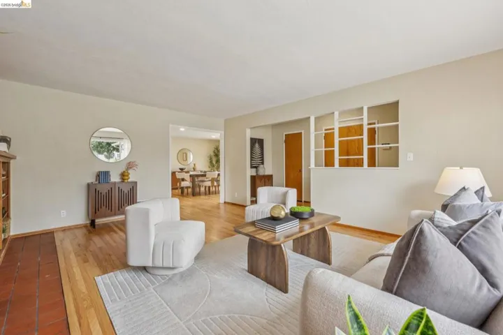 Hardwood flooring, terra cotta tile entry, light-toned walls, and a decorative partition wall