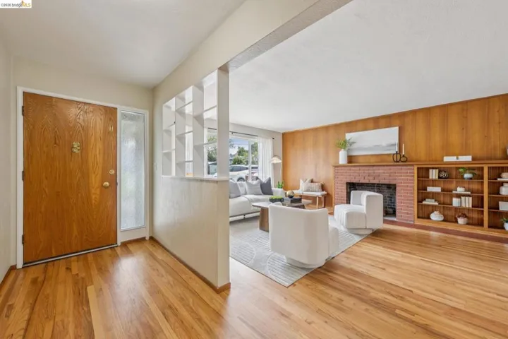 Hardwood flooring, wood paneling, brick fireplace, built-in shelving, and transom window