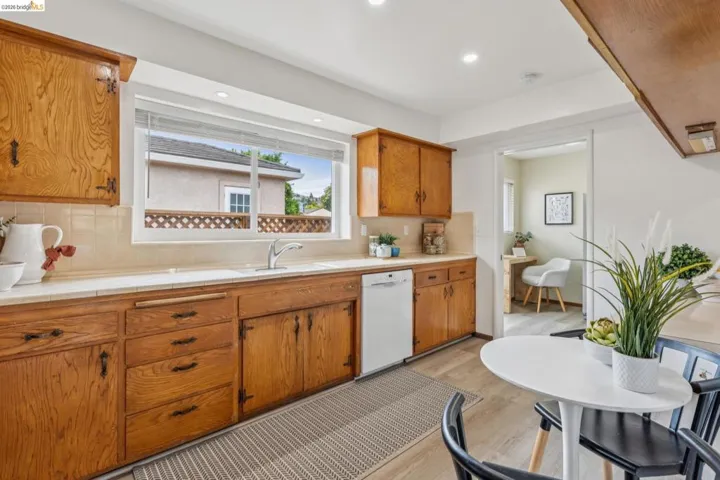 Kitchen featuring wood cabinetry, white countertops, tile backsplash, and a stainless steel sink