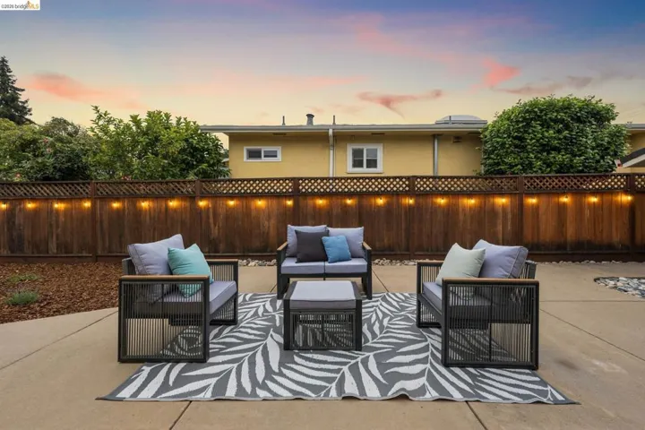 Hardscaping patio surface with a wood-panel fence and lattice top, illuminated by string lighting