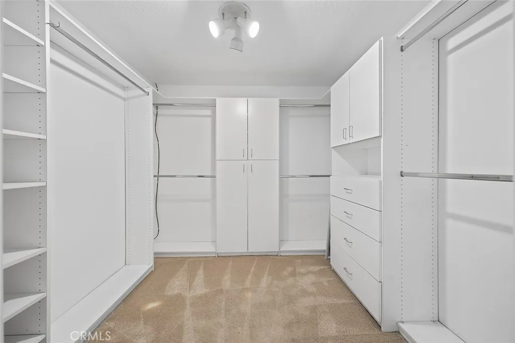 Primary walk-in closet with custom built-in storage with shelves, drawers and plenty of hanging space.