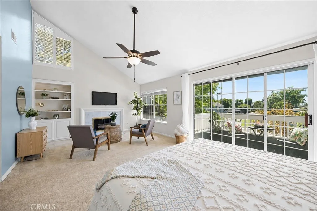 Primary bedroom has vaulted ceilings, fireplace, built-in cabinet, lighted ceiling fan and tons of natural light.
