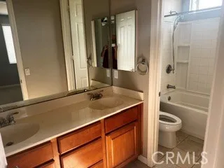 Bathroom featuring dual-sink vanity, large mirror, and separate tub/shower area.