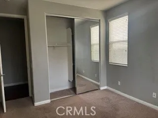 Bedroom featuring mirrored closet doors, natural light, and neutral carpeting.