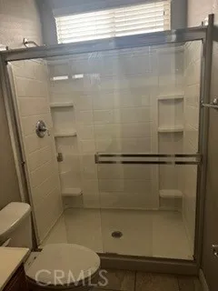Bathroom featuring a spacious glass-enclosed walk-in shower with built-in shelving.