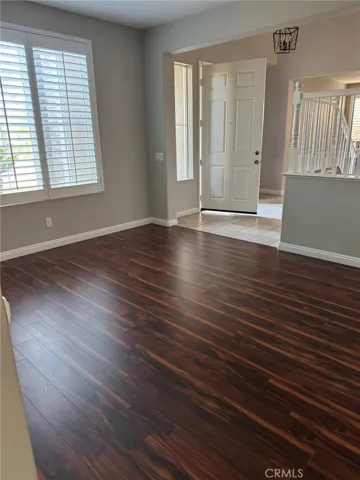 Entry & Living Area – Bright and inviting living space featuring rich wood-style flooring, plantation shutters, and easy access to the front entry.